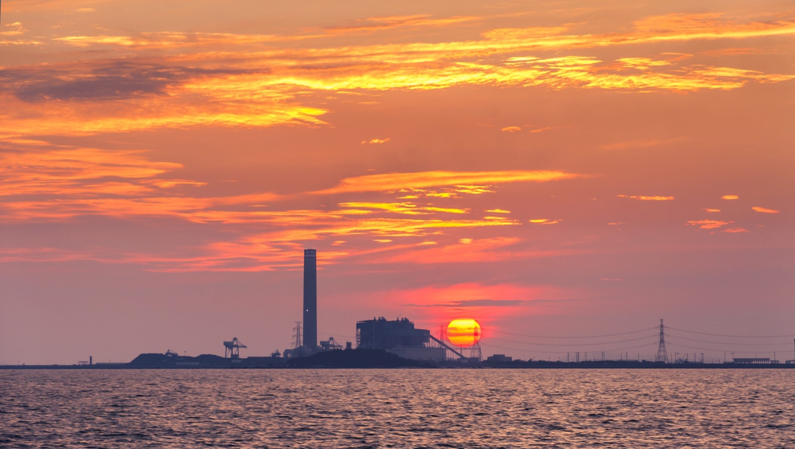 A power-generation site silhouetted against a sunset