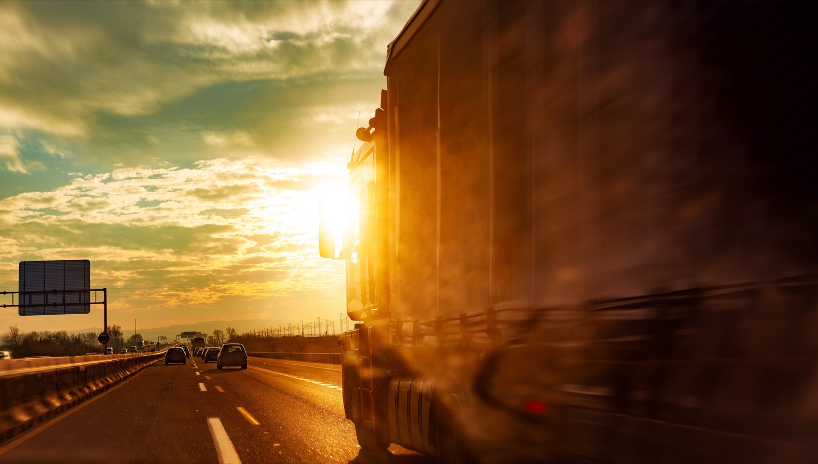 Haulage trucks driving into a warm sunset