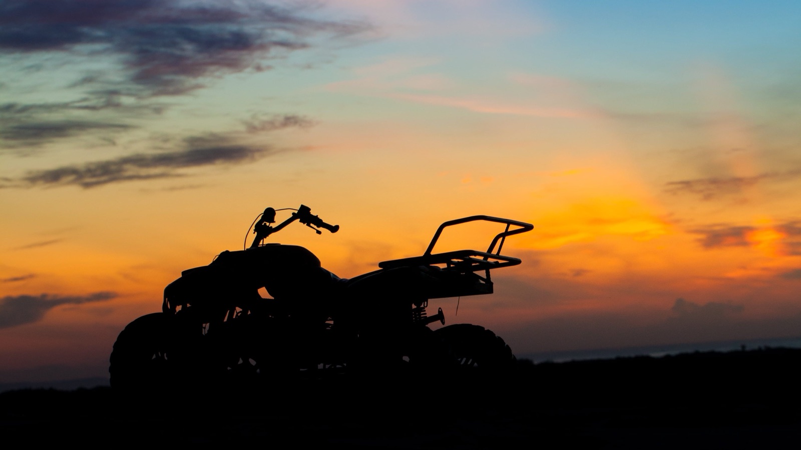 An ATV silhouetted against a colourful sunset